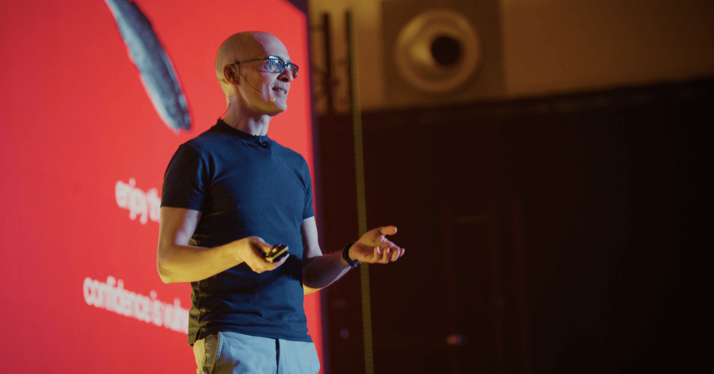 Matteo Cassese speaking on a red-lit stage at Station Berlin