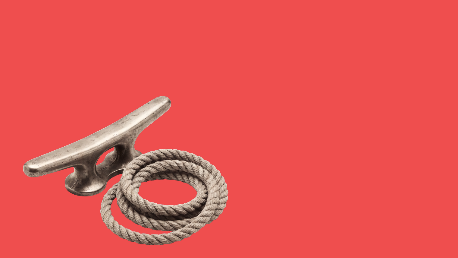 A metal mooring cleat beside a coiled rope on a red ground